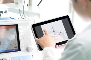 Doctor compares tablet information with ECG monitor